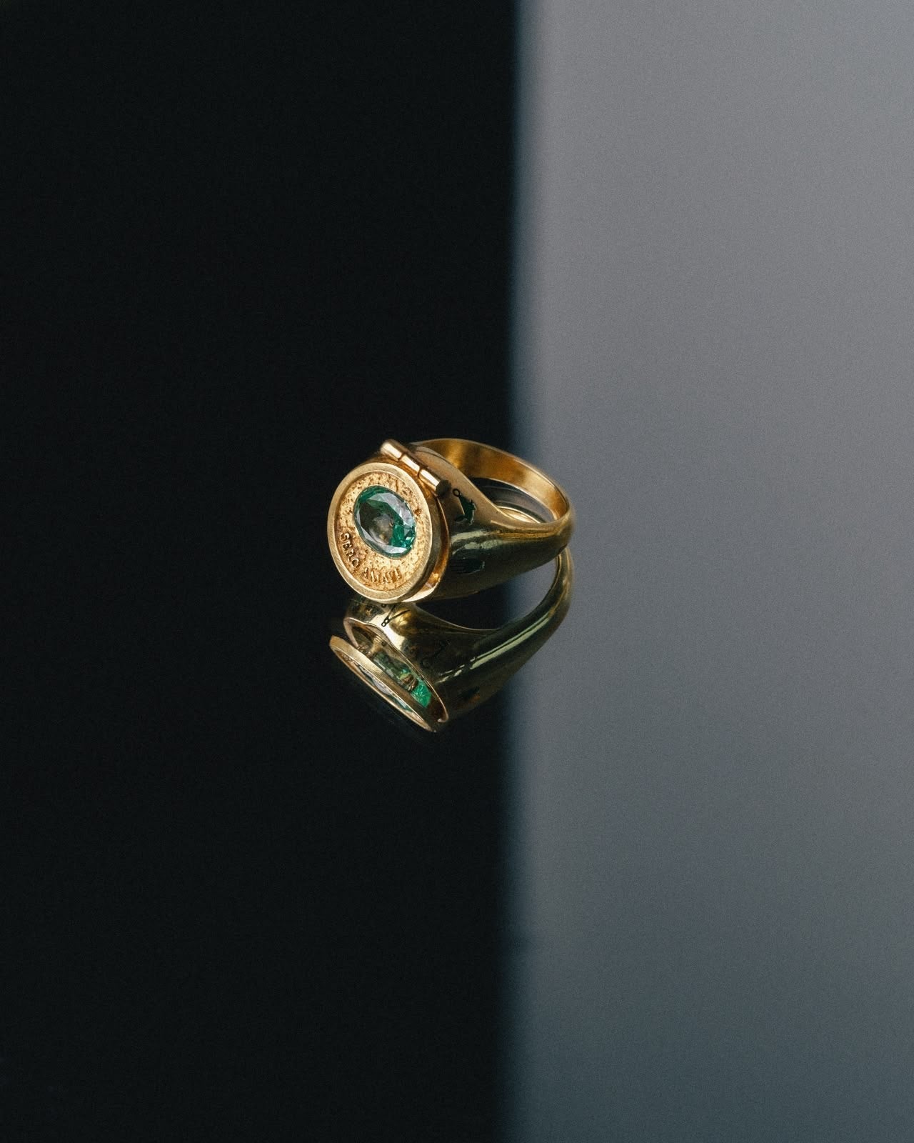 Bague poison en or avec pierre précieuse verte émeraude et détails ciselés sur fond noir