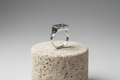 Bague poison en argent moderne avec pierre turquoise sur présentoir en pierre poreuse