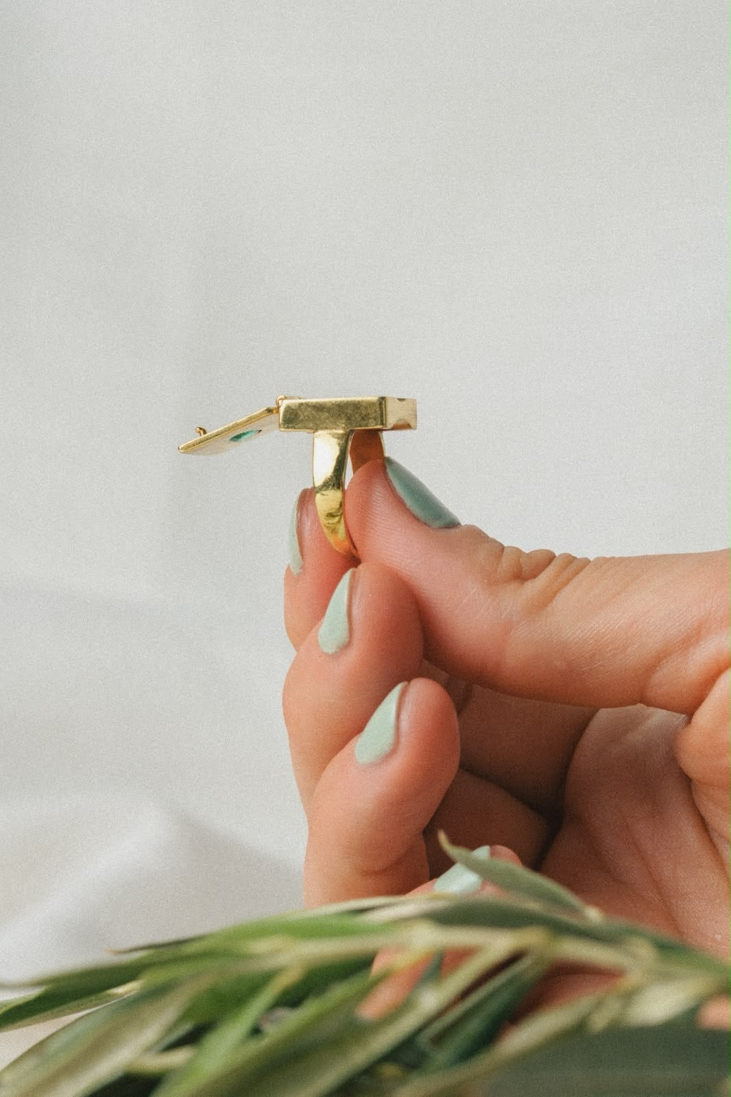 Femme tenant une bague poison entre ses doigts aux ongles vert menthe